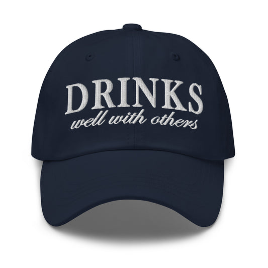 Embroidered dad hat in navy with "DRINKS well with others" front embroidery