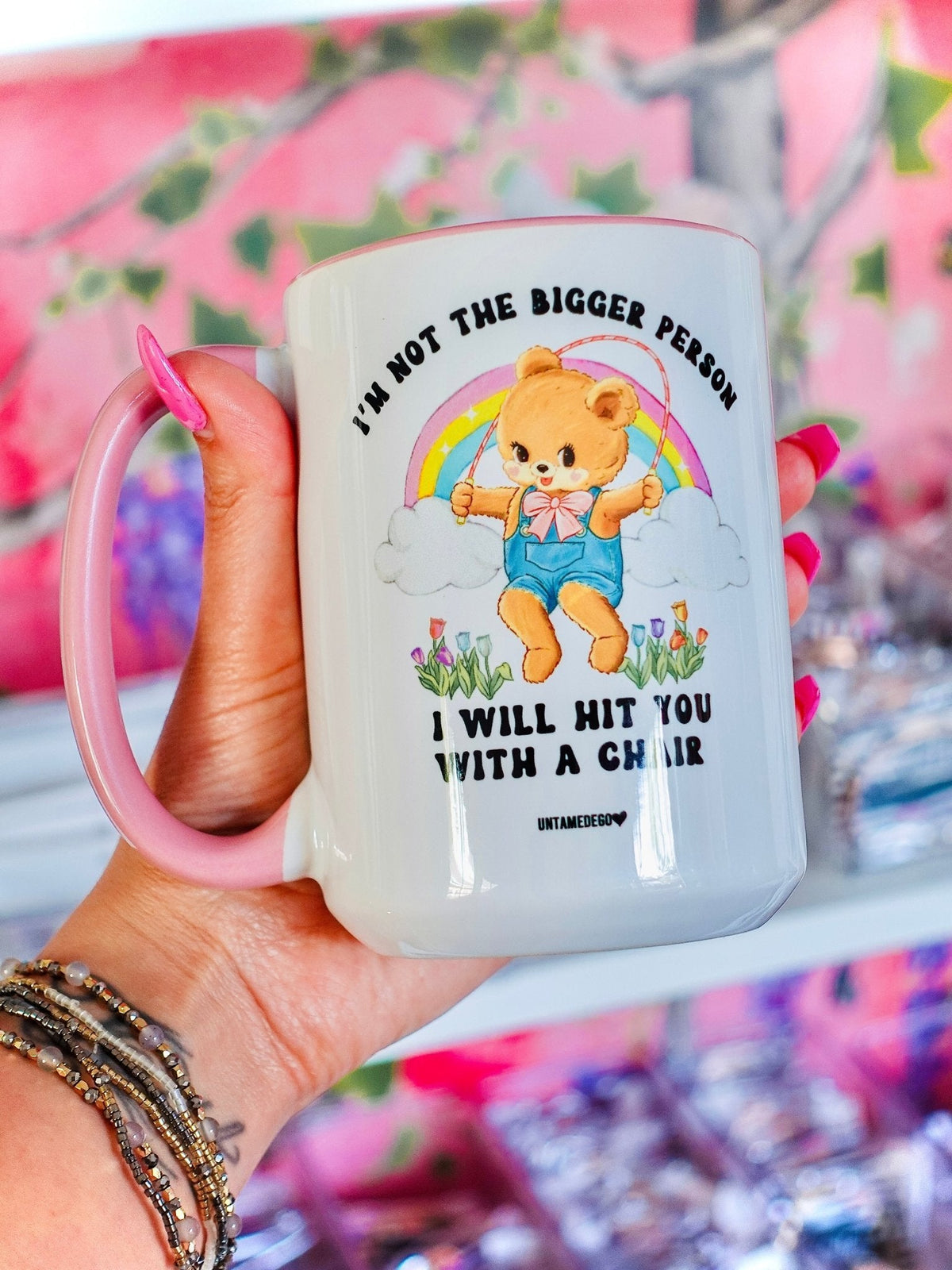 Funny "I'm Not The Bigger Person I Will Hit You With A Chair" — White ceramic mug held in hand, with angel bear rainbow graphic and quote text
