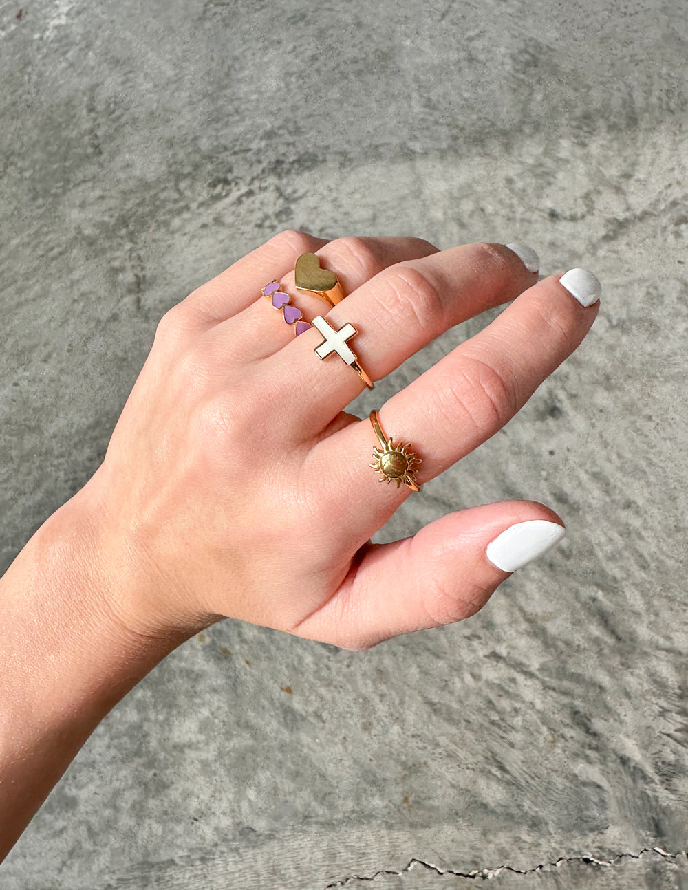 Hand wearing multiple Elevated Faith rings including a cross, representing Christian Jewelry style