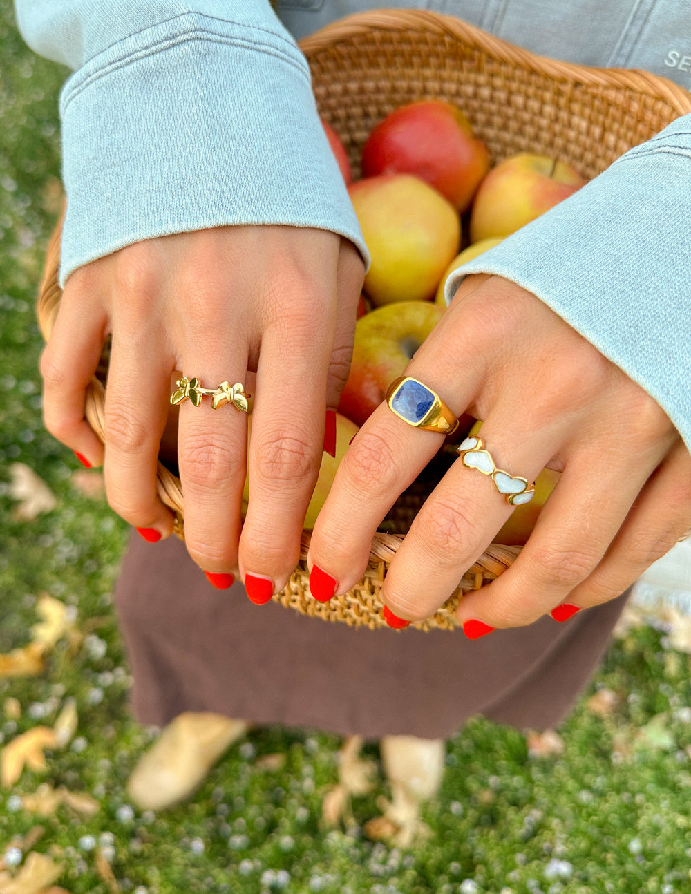 Two stylish rings from Elevated Faith showcased as Christian Jewelry worn with a basket of apples