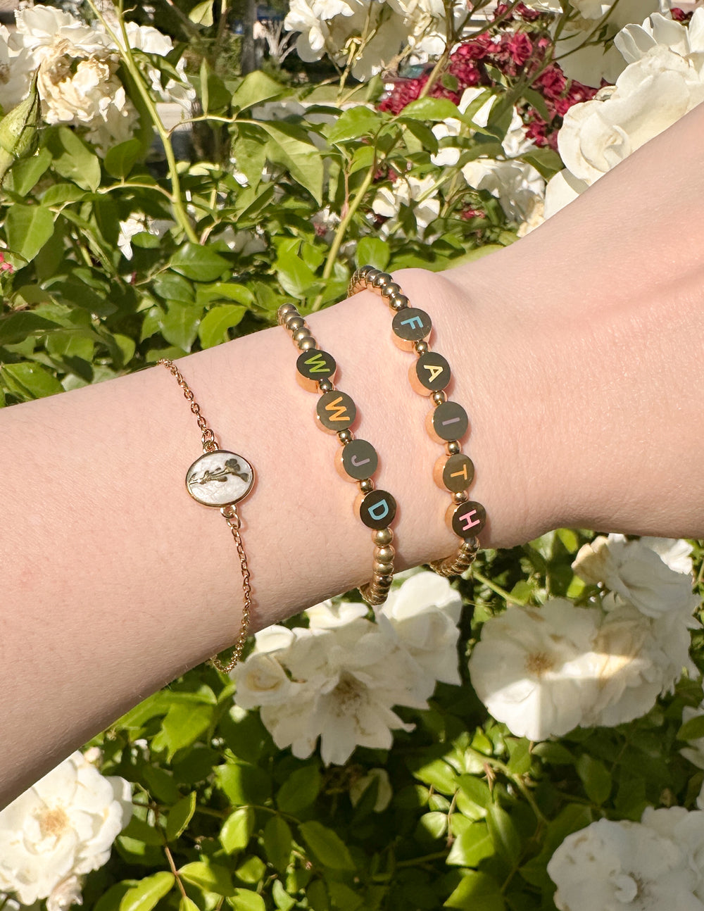 Christian Jewelry Bracelet featuring beads with letters spelling FAITH, worn on a wrist among blooming flowers