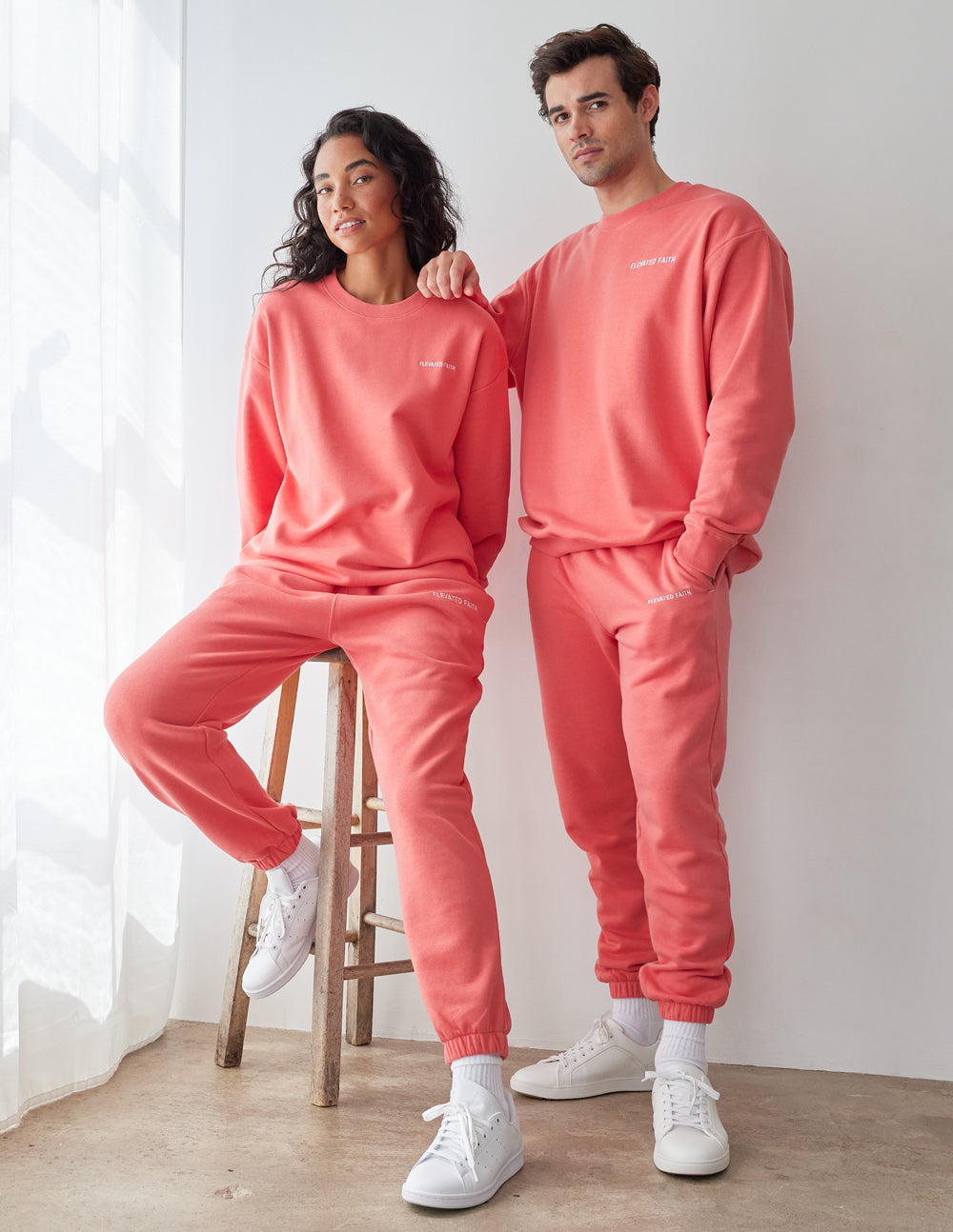 Two models wearing Elevated Faith Christian Crewneck Sweatshirt in a vibrant coral color with stylish design
