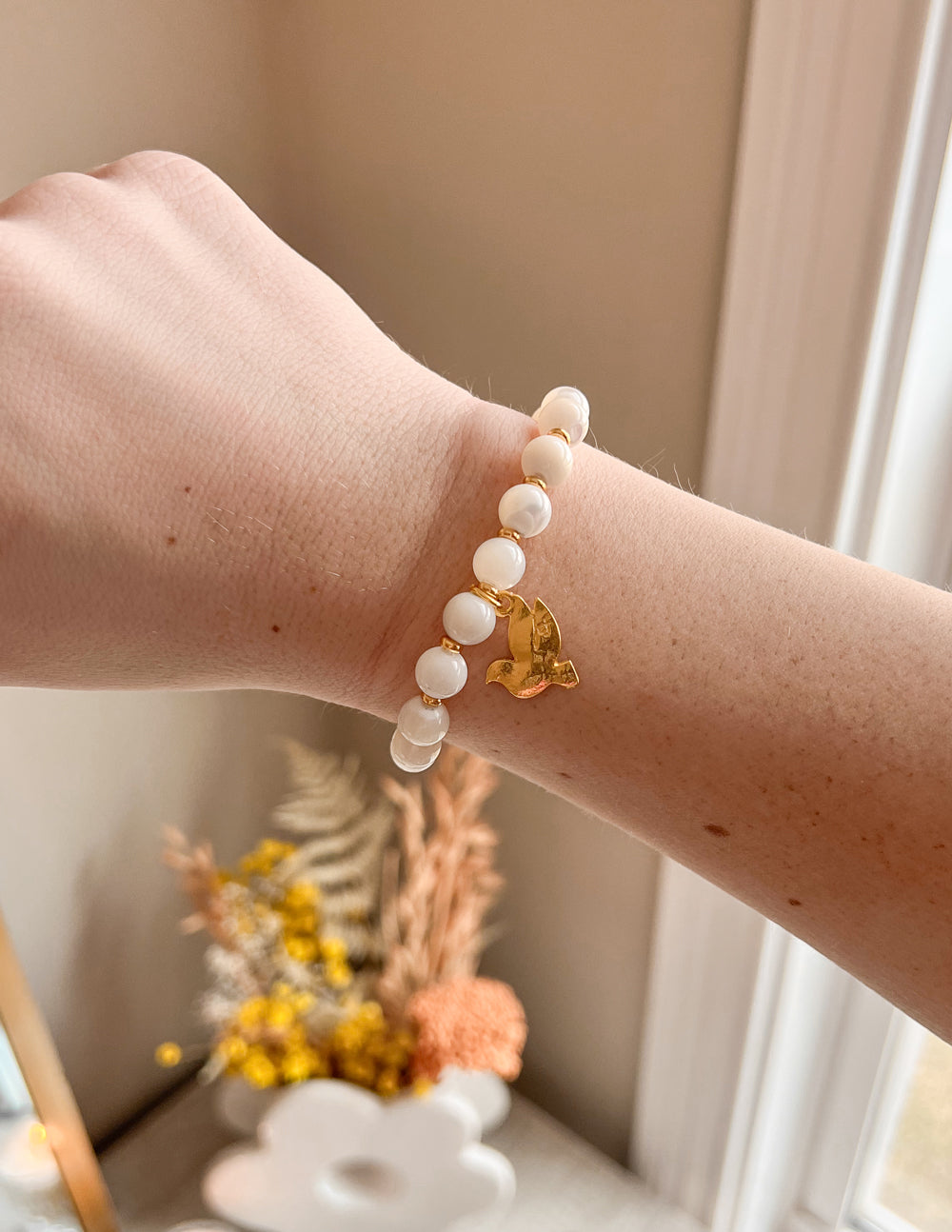Elevated Faith Christian Jewelry Bracelet featuring white stones and a gold dove charm on a wrist