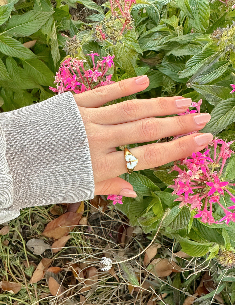 Elevated Faith Christian Jewelry Gold Heart Ring with a Pearl Design Adorning a Hand Among Flowers