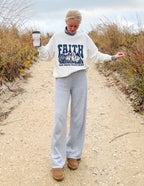 Woman wearing a white Christian Crewneck Sweatshirt with graphic text, styled casually outdoors