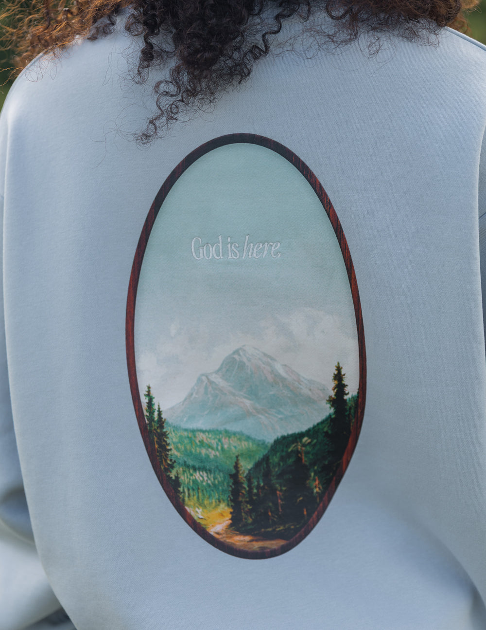 Elevated Faith Christian Crewneck Sweatshirt featuring a scenic mountain graphic with the text God is here