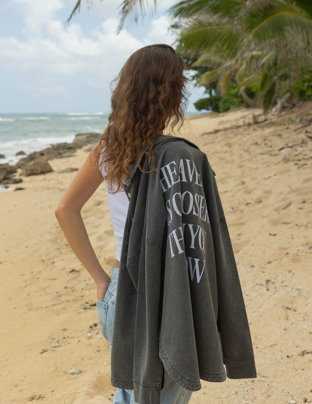 Woman wearing a Christian Jacket on a beach with a message on the back, showcasing relaxed style