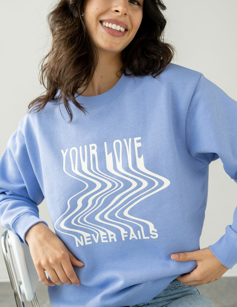 Light blue Christian Crewneck Sweatshirt with wavy design saying 'Your Love Never Fails'