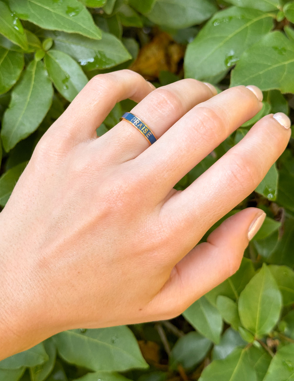 Elevated Faith Christian Jewelry Ring Featured on Hand Surrounded by Green Leaves