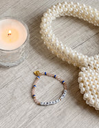 Elevated Faith Christian Jewelry Bracelet with letter beads spelling 'PERFECT LOVE' beside a candle and pearl accessories