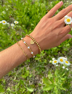 Elevated Faith Christian Jewelry Bracelet set featuring gold and pearl beads on a hand surrounded by flowers