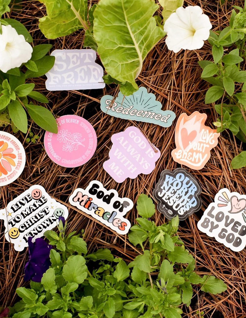 Assorted Christian Stickers on a bed of pine needles with vibrant designs and uplifting messages