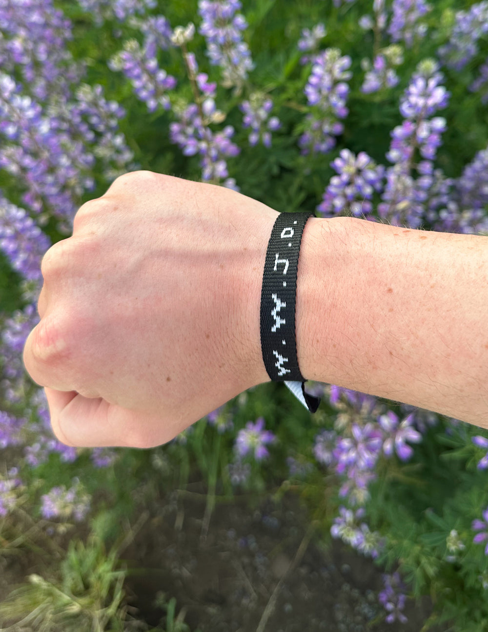 Elevated Faith Christian Jewelry Bracelet on wrist with purple flowers background for a stylish look