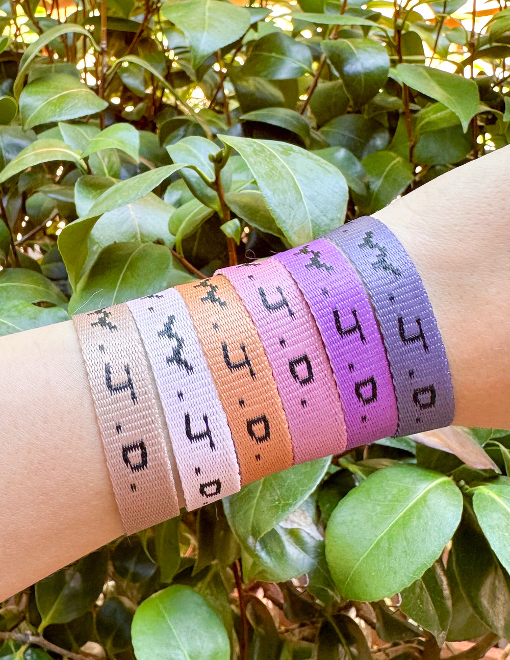 Set of colorful Elevated Faith Christian Jewelry Bracelets displayed on a wrist among green leaves