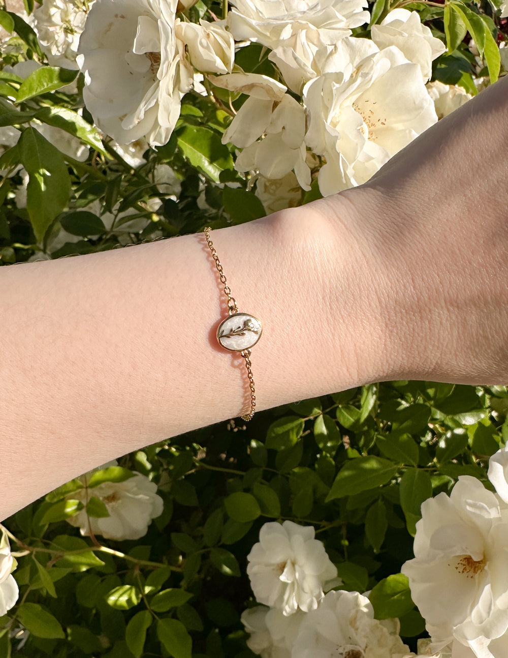 Elevated Faith Christian Jewelry Bracelet featuring a delicate design on a wrist amidst blooming flowers