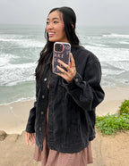 Woman holding a Christian iPhone Case by Elevated Faith while standing by the beach