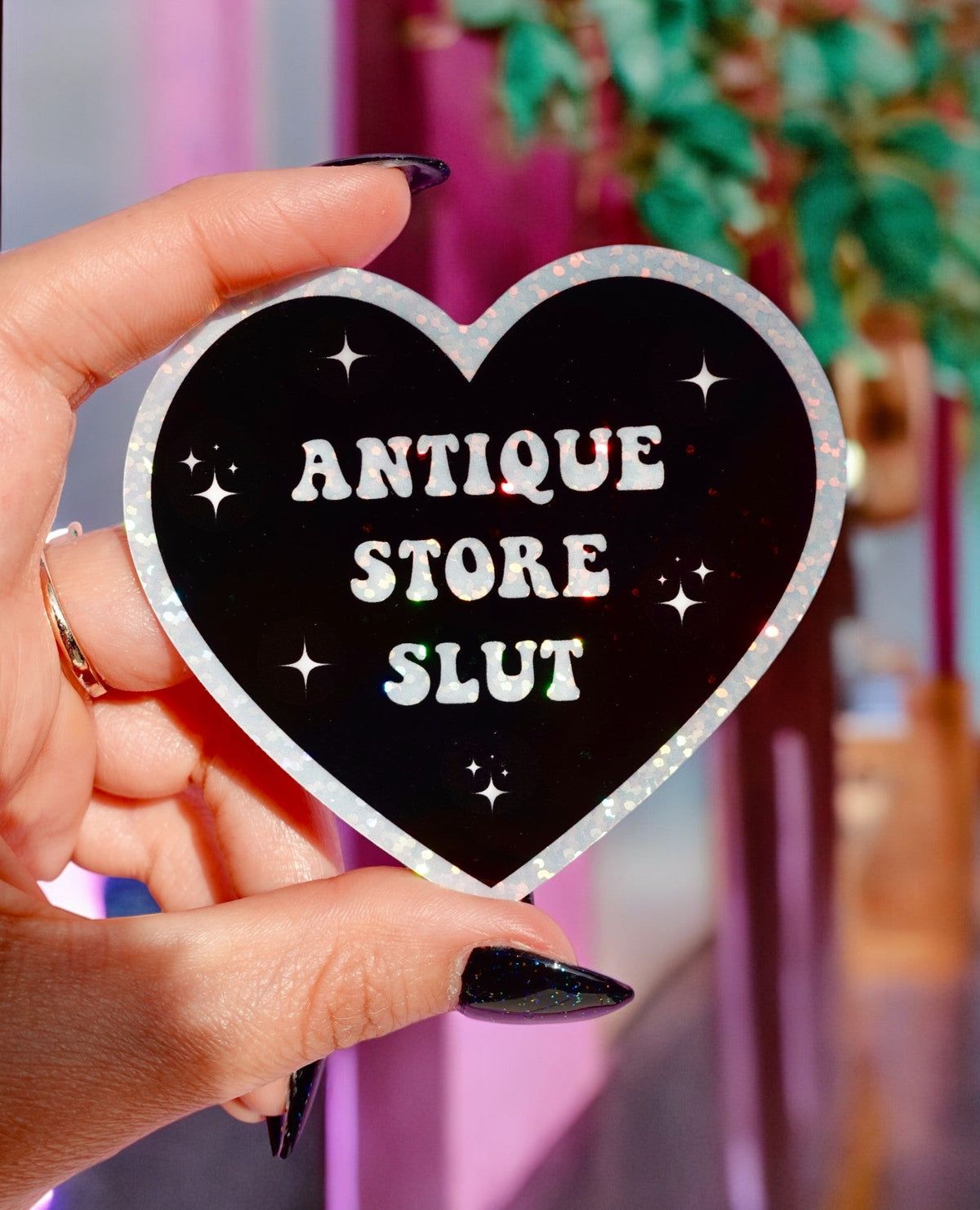 Funny Heart sticker, black with silver border; 'ANTIQUE STORE SLUT' lettering and star sparkles