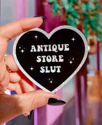 Funny Heart sticker, black with silver border; 'ANTIQUE STORE SLUT' lettering and star sparkles
