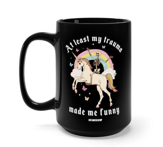 Funny "At Least My Trauma Made Me Funny" — Black ceramic mug with unicorn and skeleton graphic and the text, 'made me funny'