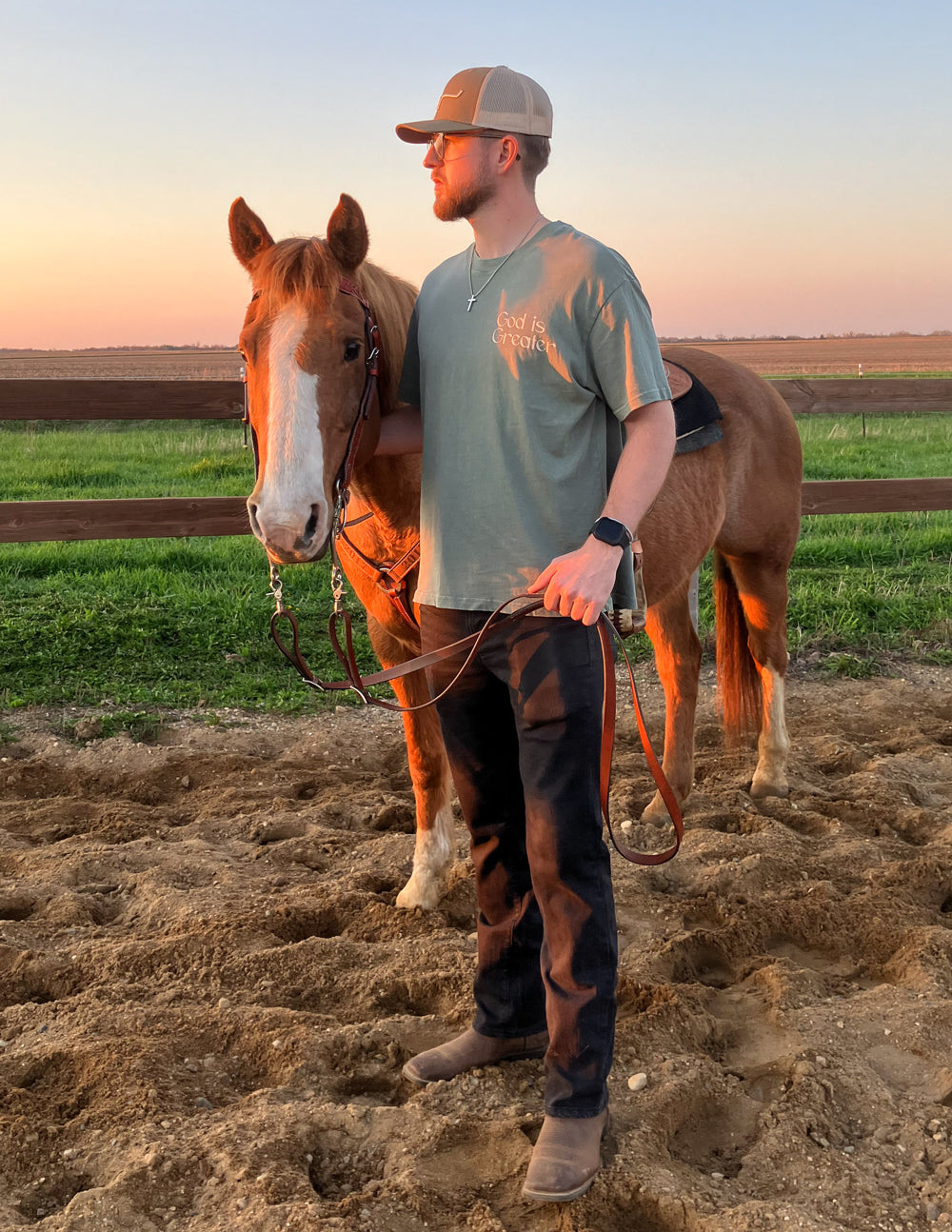Man standing beside a horse wearing an Elevated Faith Christian Apparel T-Shirt in a scenic outdoor setting