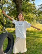 Woman wearing a light gray Christian Apparel T-Shirt, enjoying outdoor scenery with a tire swing