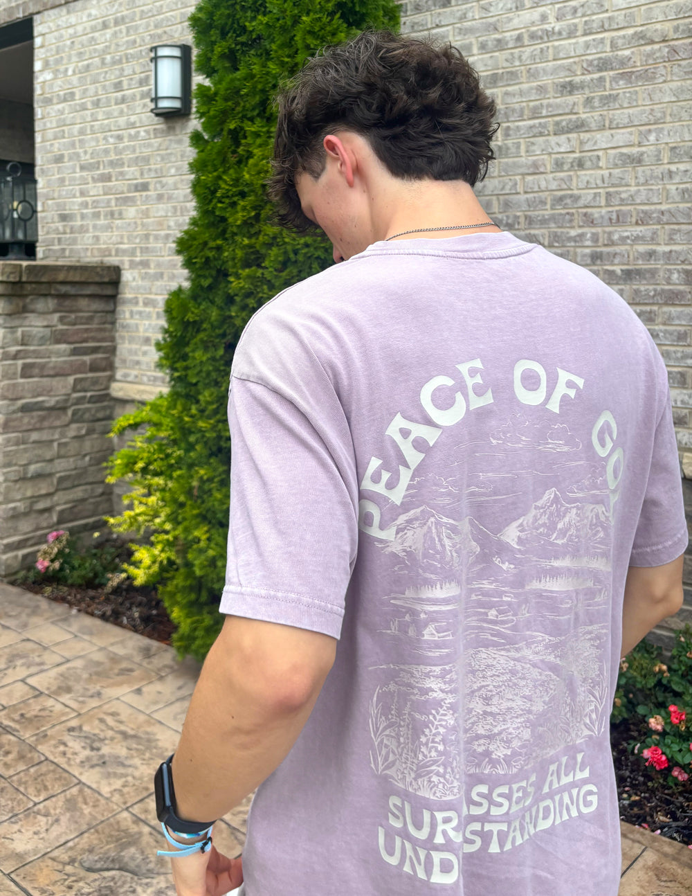 Back view of a lavender Elevated Faith Christian Apparel T-Shirt featuring mountain graphics and the words Peace of God