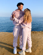 Couple wearing Elevated Faith Christian Hoodie in soft pink near the water for a stylish look