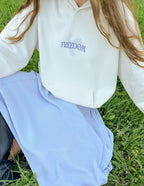 Elevated Faith Christian Hoodie in white with 'FREEDOM' graphic, styled with a pastel skirt