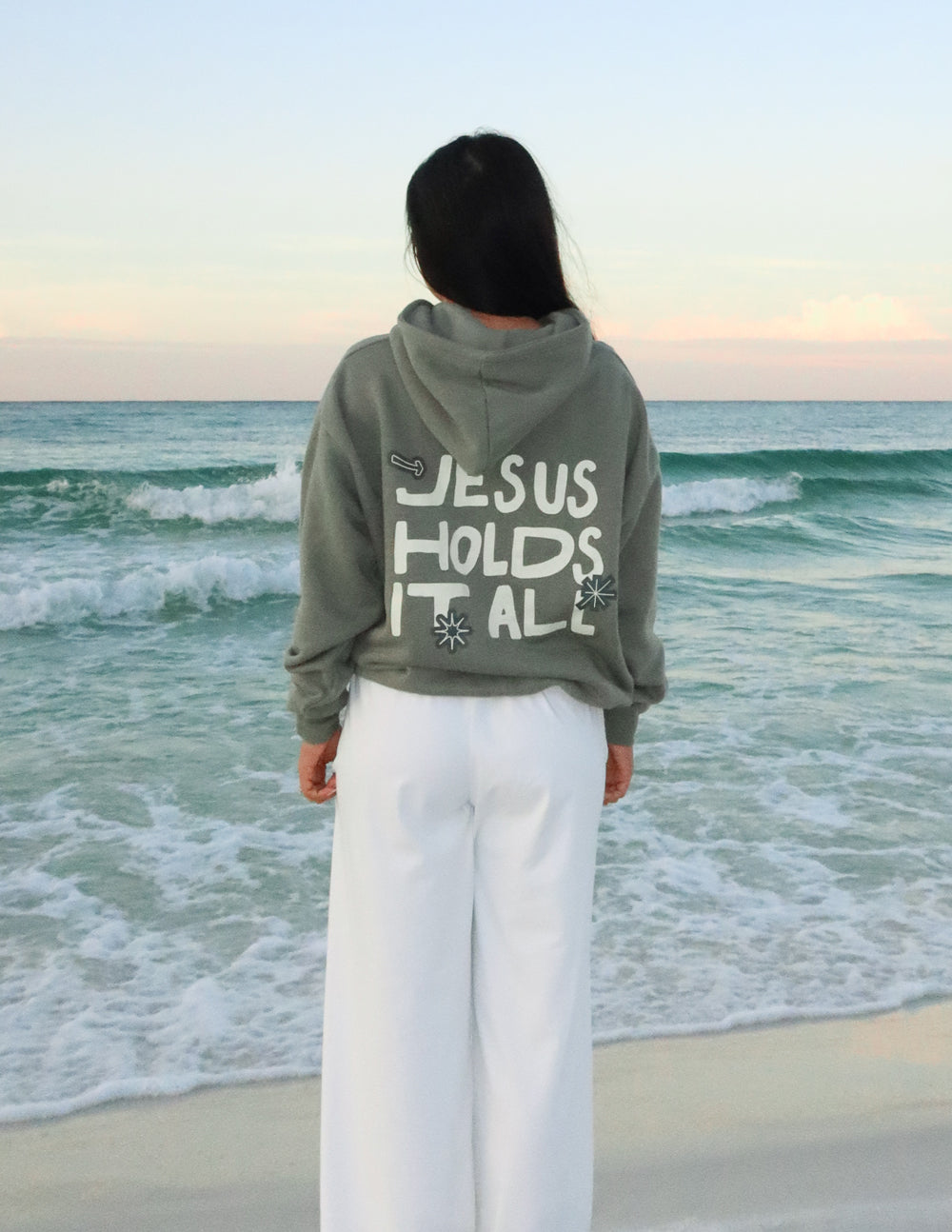 Elevated Faith Christian Hoodie with 'Jesus Holds It All' design, perfect for coastal wear