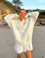 Woman wearing a cozy Elevated Faith Christian Hoodie on the beach with a joyful expression