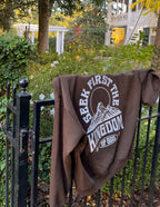 Brown Christian Hoodie with 'Seek First the Kingdom of God' Graphic Design on a Fence