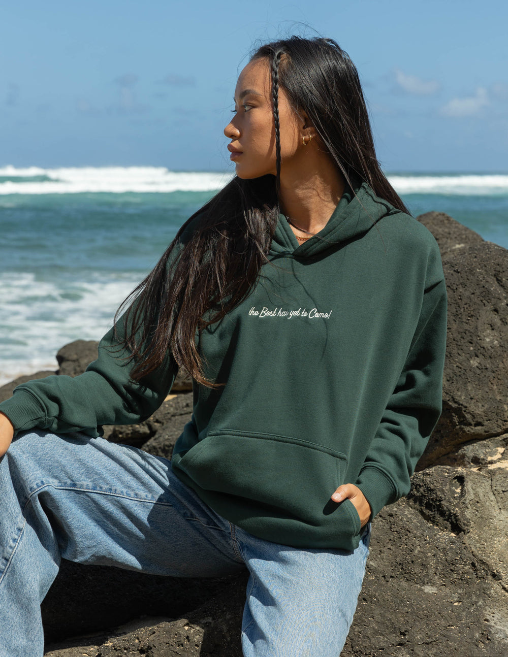 Elevated Faith Christian Hoodie in dark green featuring inspirational text by the beach