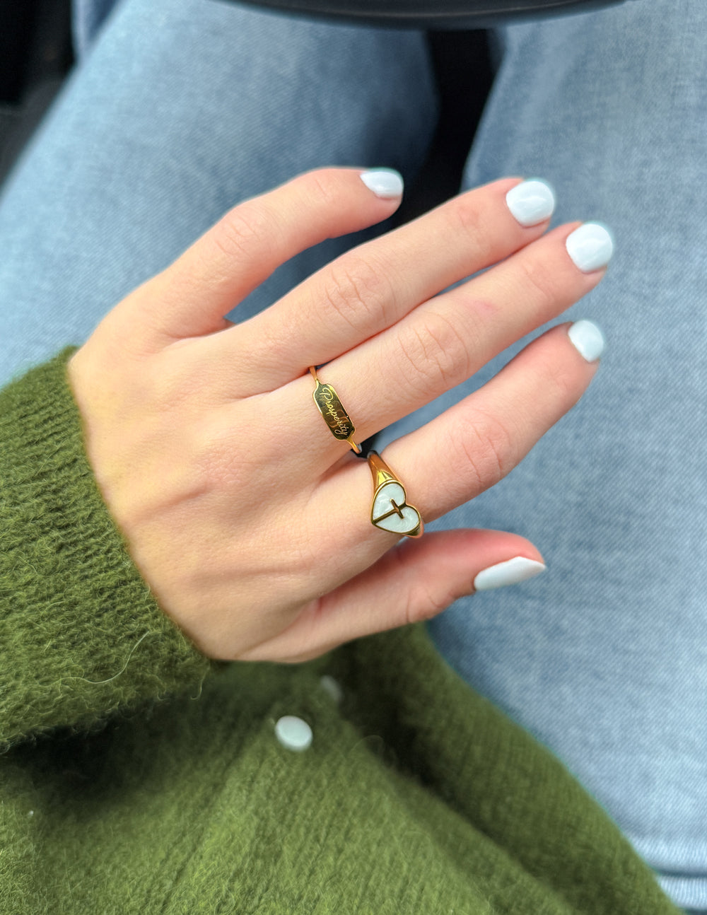 Elevated Faith Christian Jewelry Ring on a hand with a green sweater and light blue nails