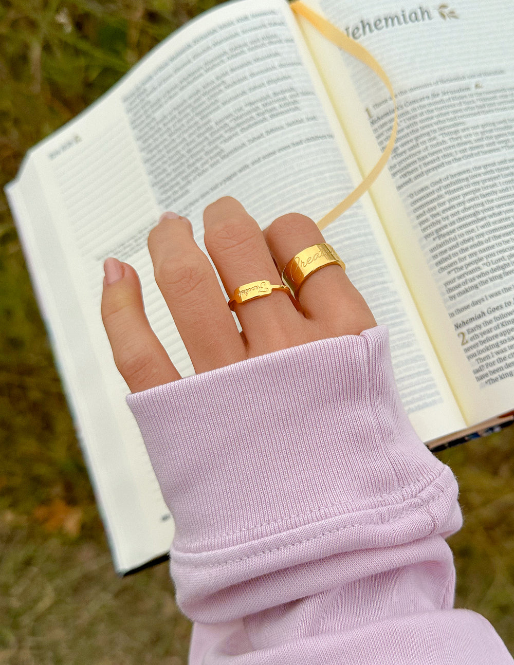Gold Elevated Faith Ring Designed as Christian Jewelry on a Hand Holding a Bible