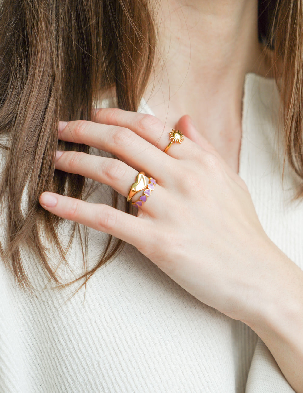 Elevated Faith Christian Jewelry Ring Stack including a gold heart and colorful band on a model's hand