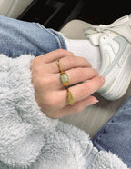 Elevated Faith Christian Jewelry gold ring with a green stone worn on a hand in a cozy outfit