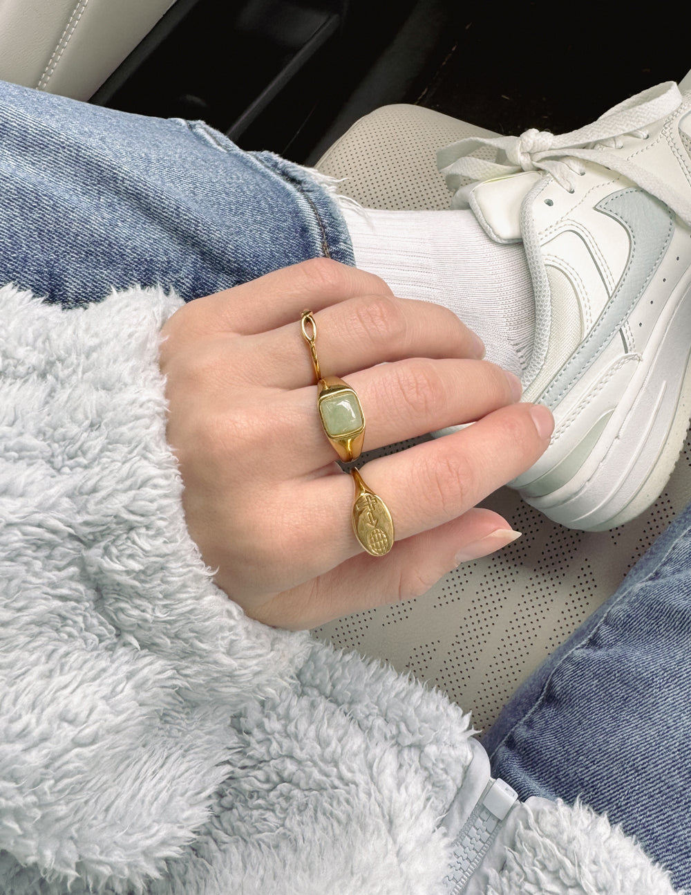 Elevated Faith Christian Jewelry gold ring with a green stone worn on a hand in a cozy outfit