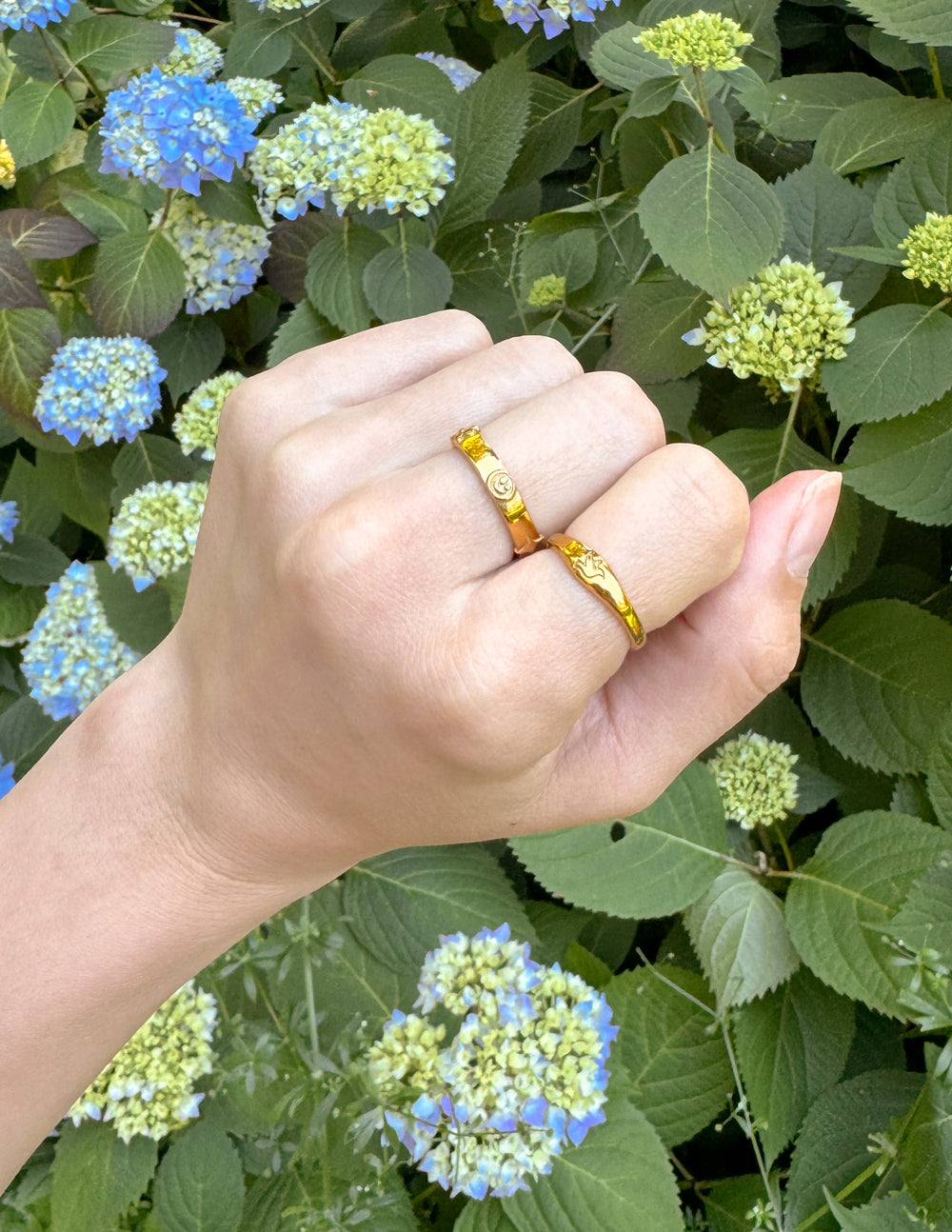 Elegant gold rings showcasing Christian Jewelry, worn on a hand amid floral background