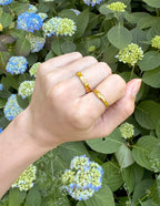 Elegant gold rings showcasing Christian Jewelry, worn on a hand amid floral background