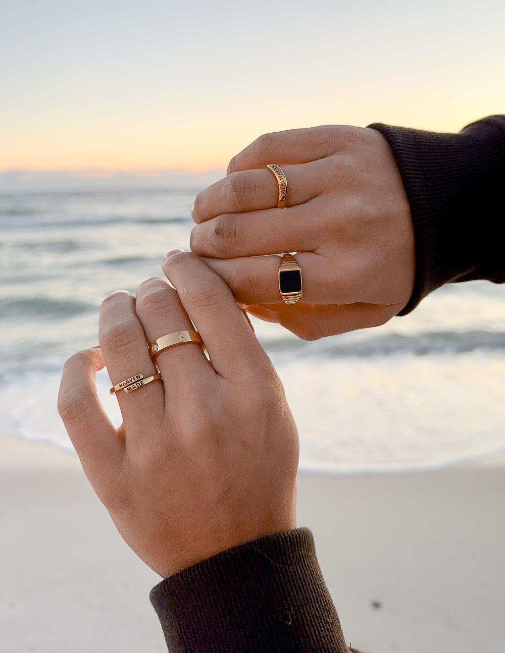 Elevated Faith Christian Jewelry rings worn on hands by the beach during sunset