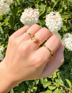 Elevated Faith Christian Jewelry gold ring set worn on hand among blooming flowers