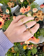 Elevated Faith Christian Jewelry Rings shown on hand with colorful floral background