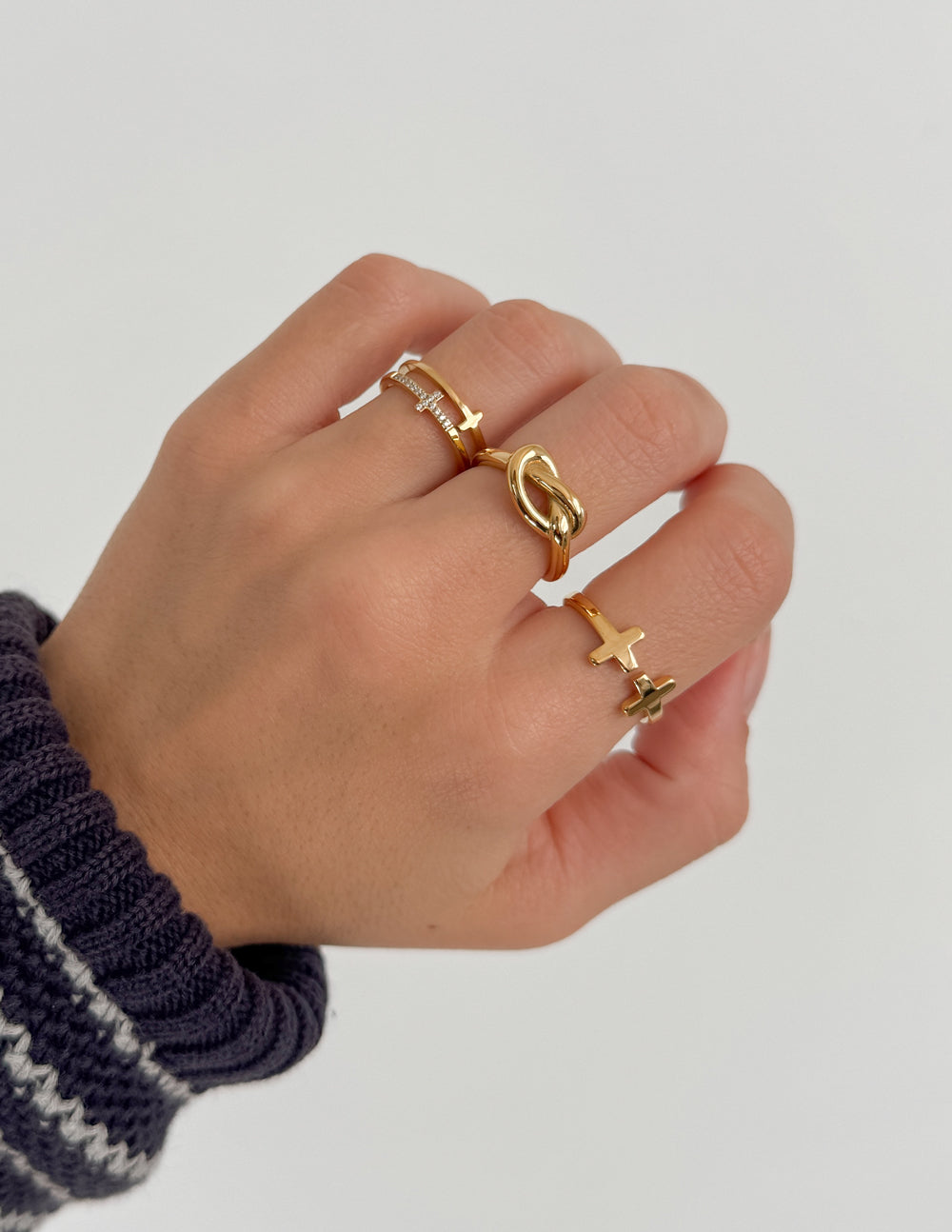 Gold Christian Jewelry rings stacked on a hand showcasing faith-inspired designs