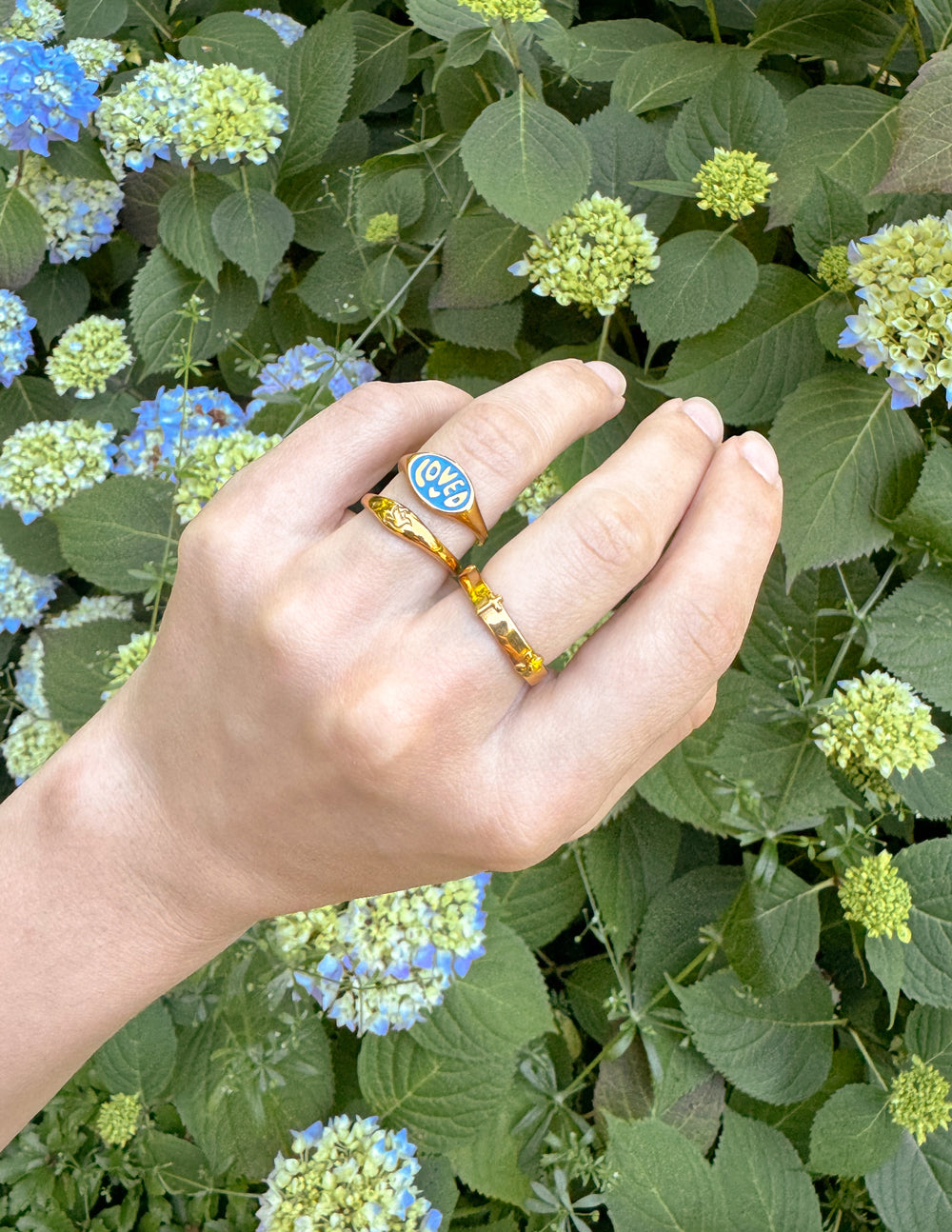 Elevated Faith Christian Jewelry Ring with Colorful Design on Hand among Green Leaves