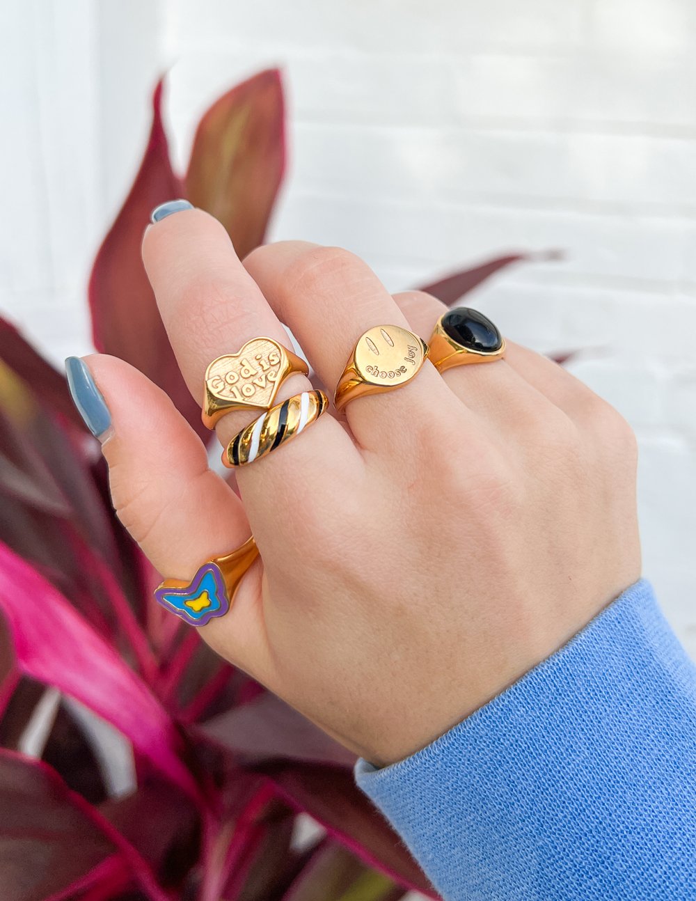 Collection of Elevated Faith Christian Jewelry rings in gold, black, and colorful designs on a hand
