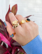 Collection of Elevated Faith Christian Jewelry rings in gold, black, and colorful designs on a hand