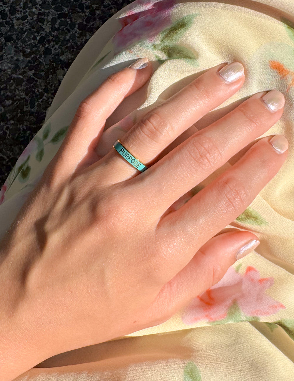 Elevated Faith Christian Jewelry Ring with a purpose inscription on a hand with a floral background
