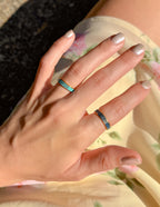 Elevated Faith Christian Jewelry Rings in Blue and Gold on a Hand Against Floral Background