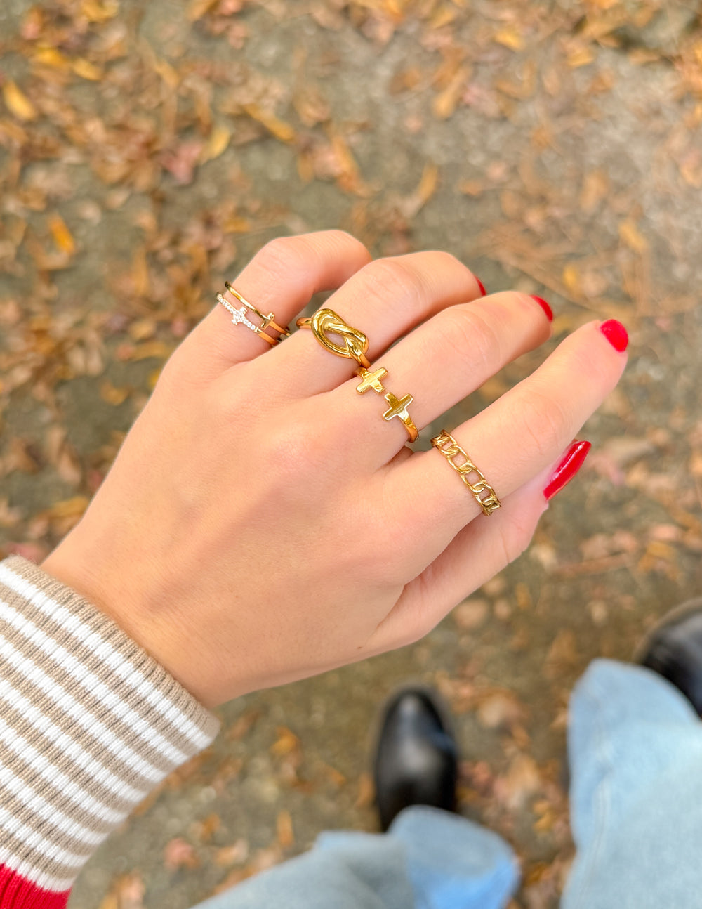 Elevated Faith gold and silver Christian Jewelry rings stacked on a hand with red nails
