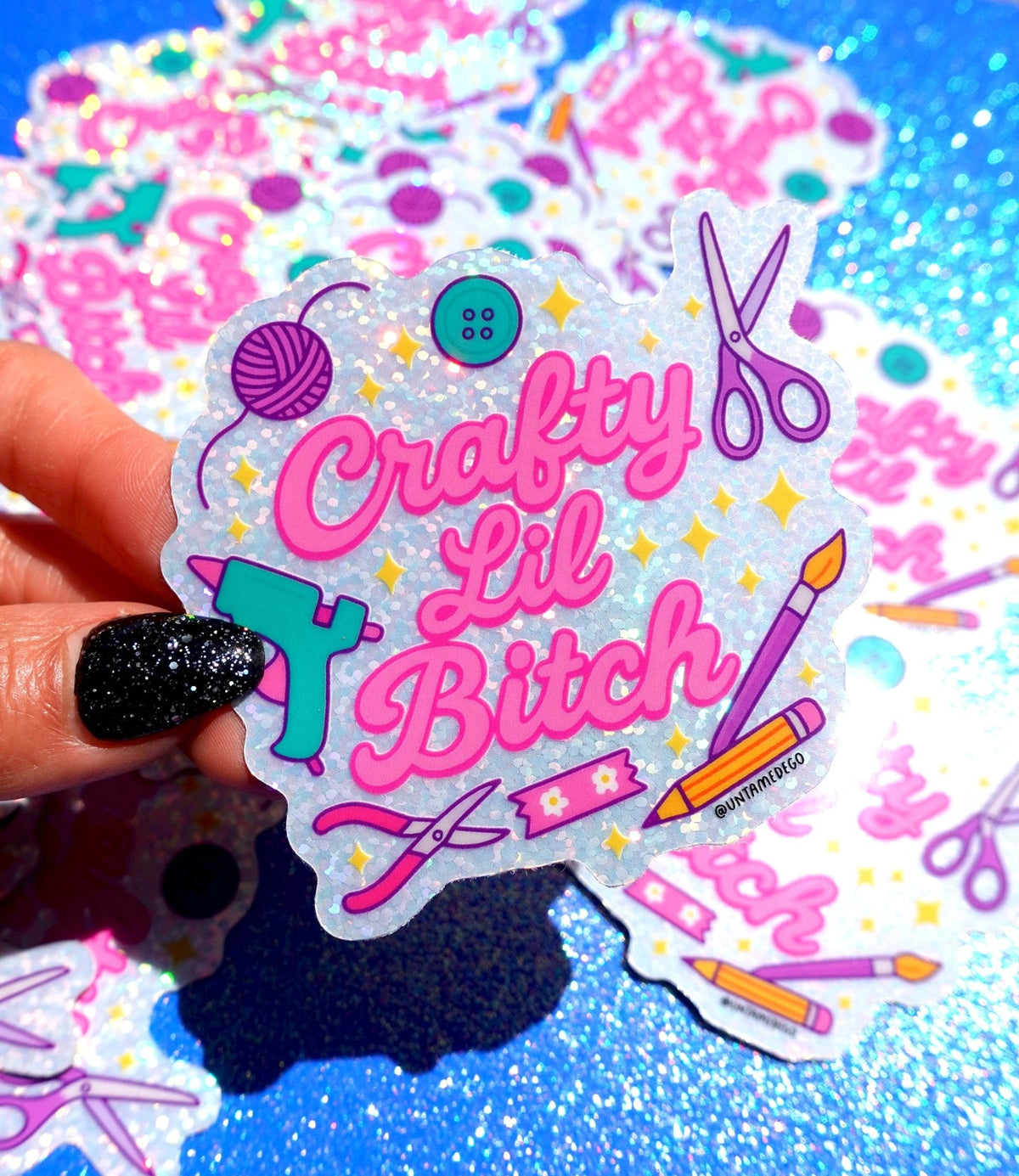 Funny Holographic die-cut sticker with purple scissors, yarn ball, button, and pink “Lil Bitch”.